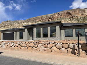 Exterior space with a garage, a mountain view, stucco siding, and stone siding
