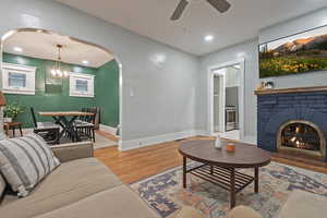 Living room with wood-type flooring, a fireplace, and ceiling fan with notable chandelier