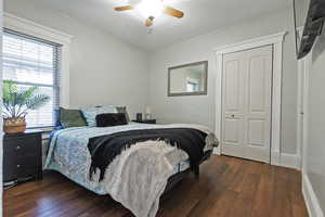 Bedroom featuring ceiling fan, dark hardwood / wood-style flooring, and a closet