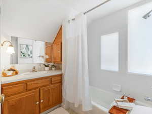 Bathroom with vanity, vaulted ceiling, and shower / bath combo with shower curtain