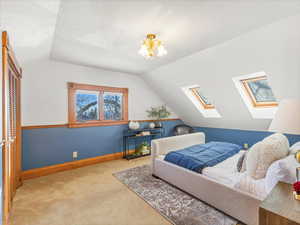 Bedroom with light colored carpet, a chandelier, vaulted ceiling, and a closet