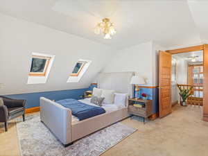 Bedroom featuring a notable chandelier, lofted ceiling with skylight, and carpet