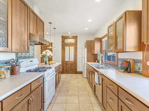 Kitchen with light tile patterned flooring, decorative light fixtures, tasteful backsplash, sink, and white appliances