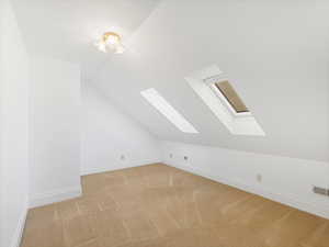 Additional living space with lofted ceiling and light carpet