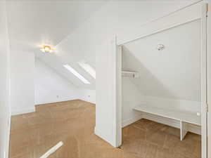 Additional living space featuring lofted ceiling with skylight and carpet