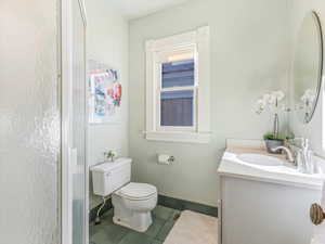 Bathroom featuring vanity, a shower with shower door, tile patterned floors, and toilet