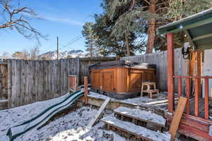 Snowy yard with a mountain view and a hot tub