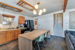 Kitchen with sink, hanging light fixtures, black appliances, a textured ceiling