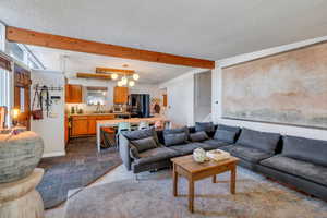 Living room featuring beamed ceiling, sink, and a textured ceiling