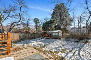 Snow covered deck with a mountain view and a storage shed