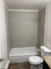 Full bathroom with vanity, a textured ceiling, tiled shower / bath combo, toilet, and baseboard heating