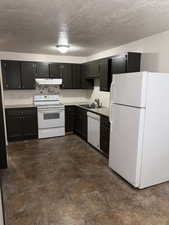 Kitchen with sink, white appliances, and a textured ceiling