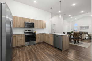 Kitchen with appliances with stainless steel finishes, dark hardwood / wood-style floors, kitchen peninsula, and sink