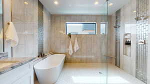 Bathroom featuring tile walls, vanity, and plus walk in shower