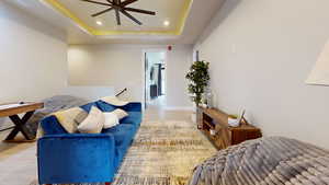 Living room featuring ceiling fan, a tray ceiling, and light hardwood / wood-style floors