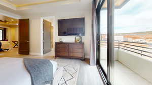 Bedroom with light hardwood / wood-style flooring, a raised ceiling, and ensuite bathroom