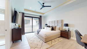 Bedroom with ceiling fan, a tray ceiling, light wood-type flooring, and access to outside