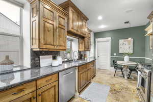 Kitchen with decorative light fixtures, sink, backsplash, granite counters, and stainless steel appliances