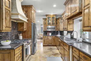 Kitchen with sink, granite countertops, backsplash, stainless steel appliances, and custom range hood