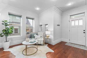 Entryway with dark hardwood / wood flooring and ornamental molding