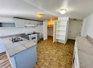 Kitchen with white cabinetry, sink, kitchen peninsula, and white gas stove