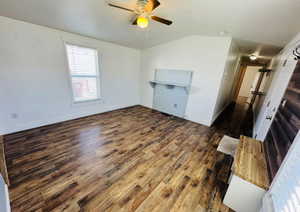 Unfurnished living room with ceiling fan, lofted ceiling, and dark hardwood / wood-style flooring