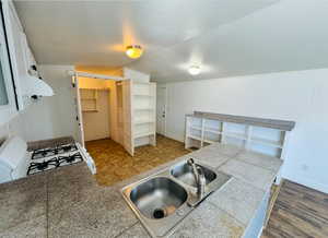 Kitchen with lofted ceiling, sink, gas range gas stove, white cabinetry, and a textured ceiling