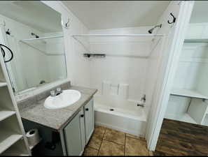 Bathroom featuring tiled shower / bath combo, vanity, and tile patterned floors