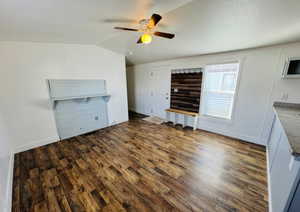 Unfurnished living room with vaulted ceiling, dark hardwood / wood-style floors, and ceiling fan