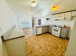 Kitchen featuring white appliances, ceiling fan, white cabinetry, light tile patterned flooring, and kitchen peninsula