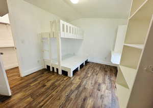 Unfurnished bedroom featuring lofted ceiling and dark hardwood / wood-style floors