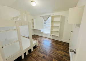 Unfurnished bedroom with vaulted ceiling and dark hardwood / wood-style flooring