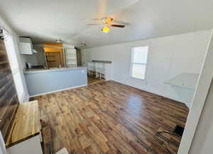 Unfurnished living room featuring dark wood-type flooring, ceiling fan, lofted ceiling, and sink