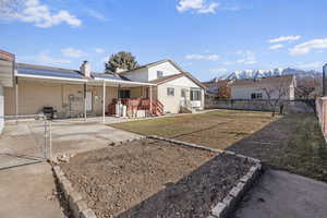 Rear view of property featuring a patio, a mountain view, a lawn, and solar panels