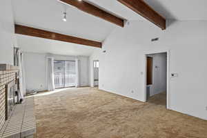 Unfurnished living room featuring high vaulted ceiling, a brick fireplace, light carpet, and beam ceiling