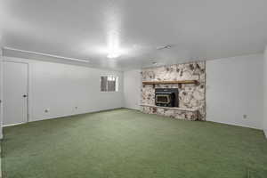 Unfurnished living room featuring a stone fireplace and carpet floors