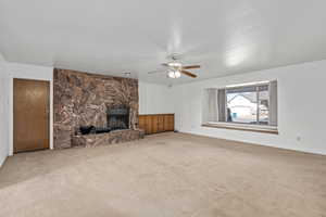 Unfurnished living room featuring ceiling fan, a fireplace, and carpet floors