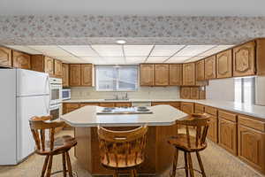 Kitchen featuring white appliances, a kitchen breakfast bar, a center island, and sink