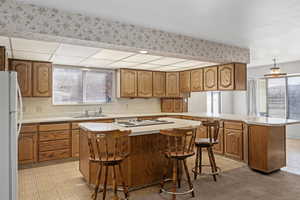 Kitchen featuring a breakfast bar, sink, kitchen peninsula, a kitchen island, and white appliances