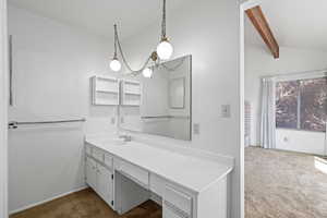 Bathroom featuring vanity and vaulted ceiling with beams