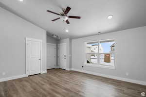 Unfurnished bedroom featuring hardwood / wood-style flooring, ceiling fan, vaulted ceiling, and two closets