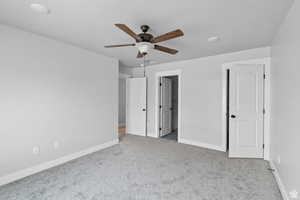 Unfurnished bedroom with light colored carpet and ceiling fan