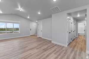Spare room featuring vaulted ceiling and light hardwood / wood-style floors