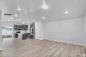 Unfurnished living room featuring light hardwood / wood-style flooring and vaulted ceiling