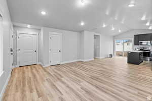 Unfurnished living room featuring lofted ceiling and light wood-type flooring