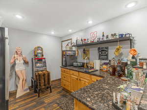 Kitchen featuring sink, dark stone countertops, and stainless steel refrigerator