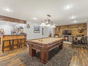 Playroom with pool table, bar area, dark hardwood / wood-style flooring, and wood walls