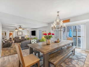 Dining room with ceiling fan with notable chandelier and light hardwood / wood-style flooring