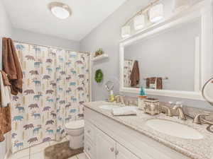 Bathroom featuring tile patterned flooring, vanity, curtained shower, and toilet