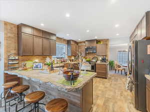 Kitchen with a breakfast bar, decorative backsplash, light hardwood / wood-style floors, kitchen peninsula, and stainless steel appliances